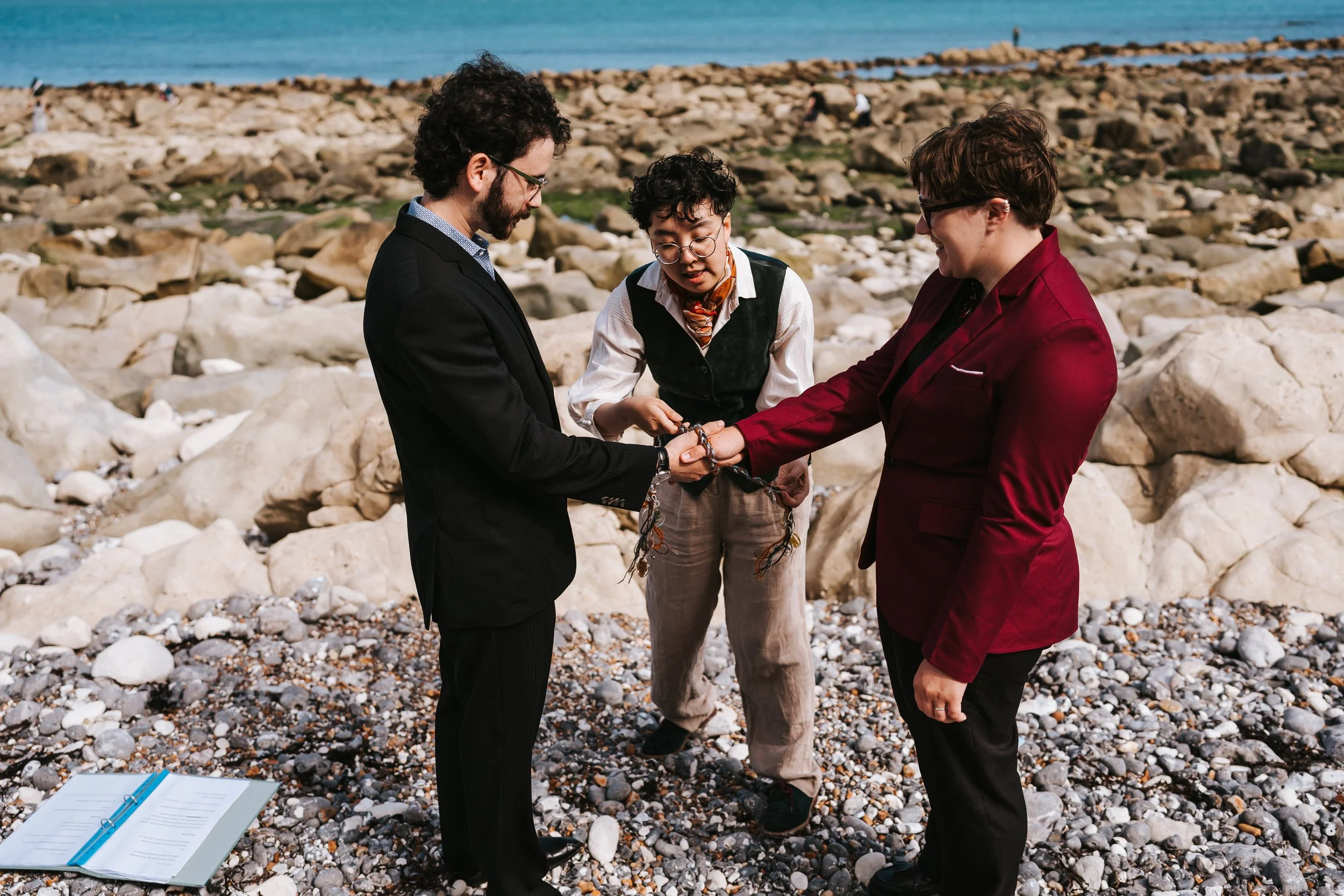 Holden the celebrant helping Brigid and Isaac tie the knot with their handfasting ritual.