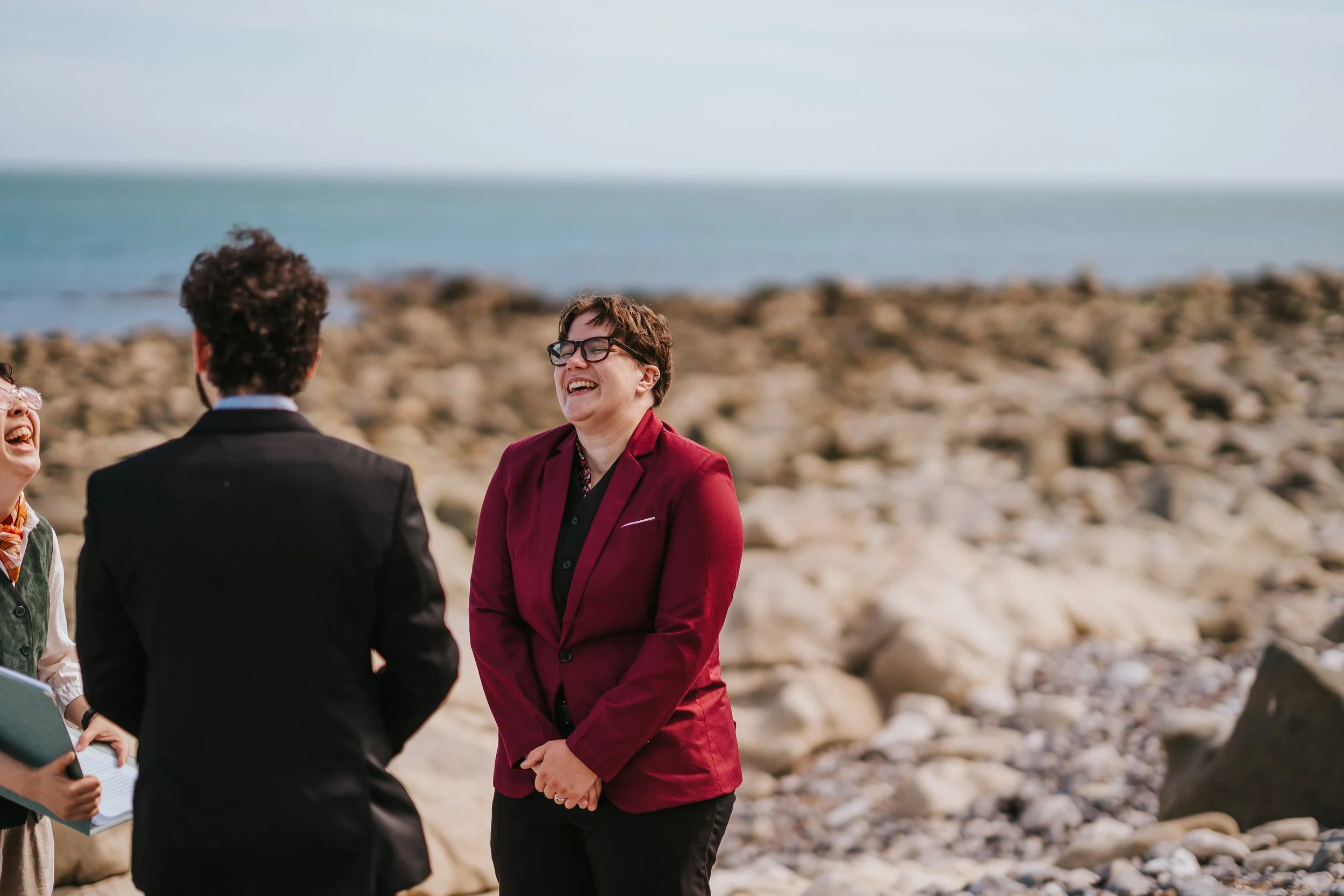 Brigid laughing during their beach elopement ceremony.