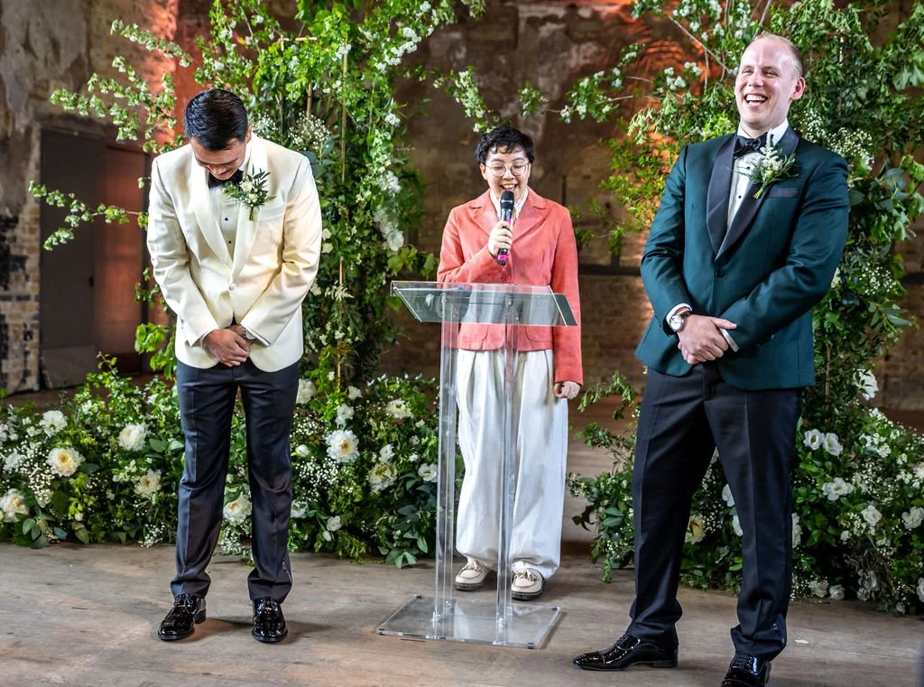 Kevin doubled over in laughter while James is also laughing, as Holden their celebrant speaks.