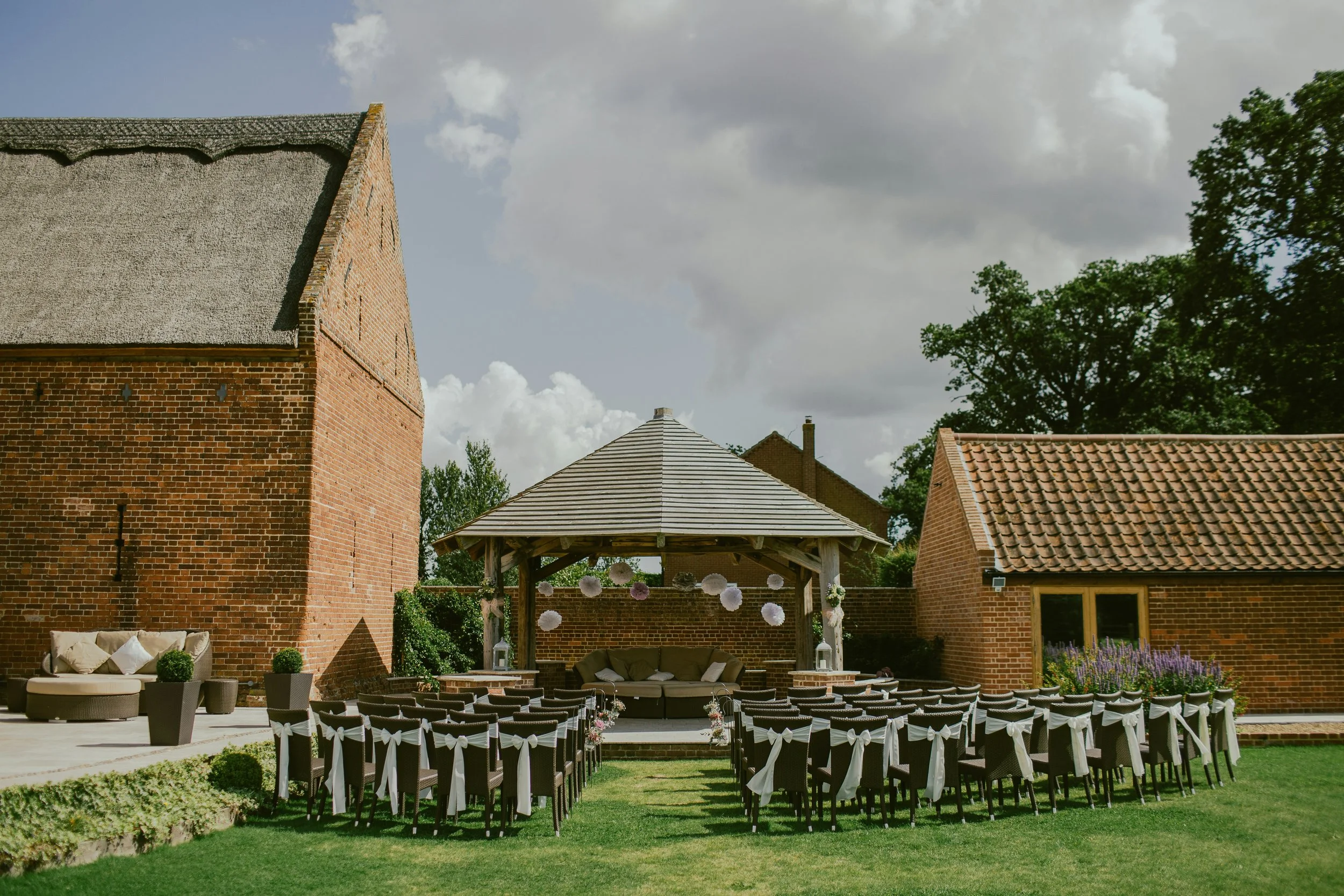 An outdoor space with a decorated gazebo and rows of empty chairs set up for a wedding ceremony