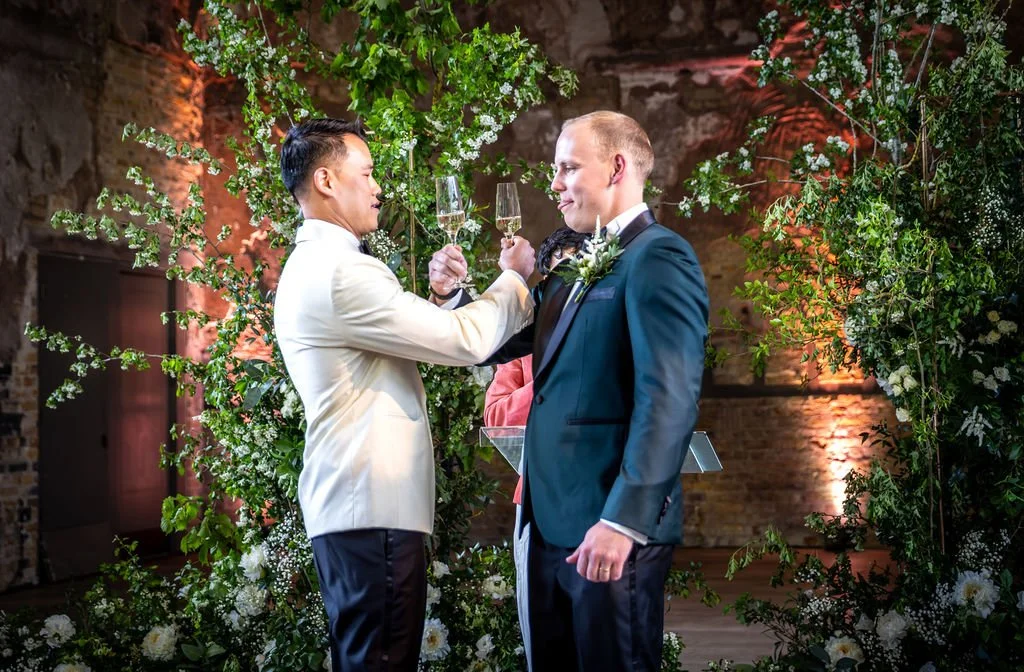 Kevin and James interlinking their arms and preparing to drink. James is sticking his tongue out in concentration!