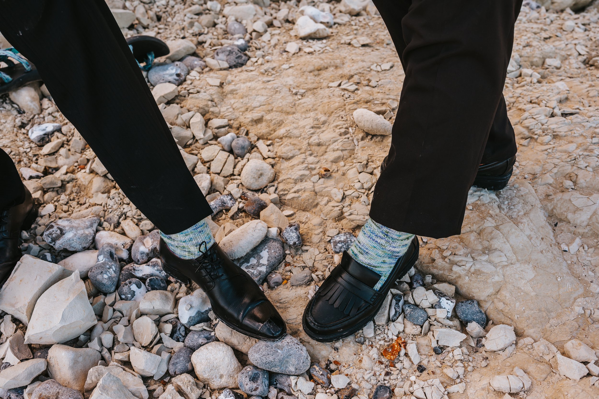 A close-up of Brigid and Isaac's black shoes and the knitted socks they're wearing.