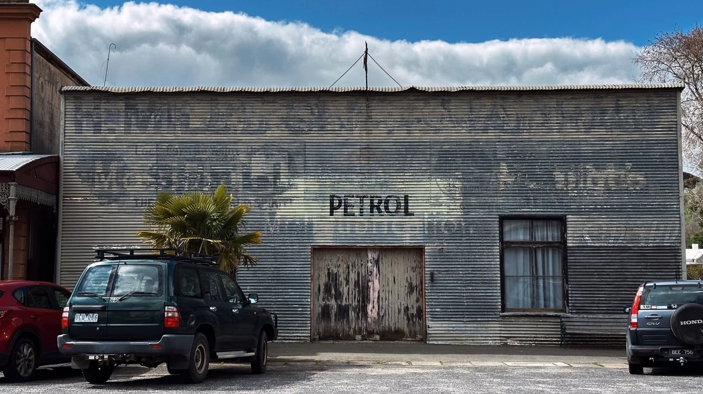 Some ghost signs fade politely. Others sit there grinning like they know where the bodies are buried.

The old Central Garage in Clunes is one of the latter.

The building at 67 Fraser Street carries a whole archaeology of motoring history on its ski