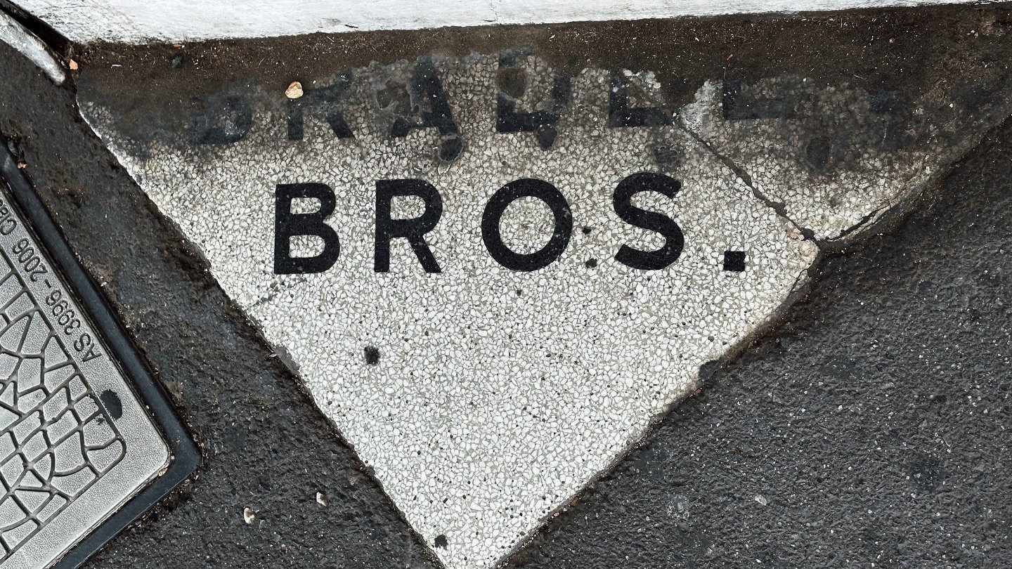 Don&rsquo;t Look Up: Bradley Bros. in Brunswick 

On Sydney Road, the ghost is not on the wall.

It is underfoot. A name worn into the old entrance threshold, scuffed by a century of boots, prams, dogs, smokers, tradies, schoolkids and people walking