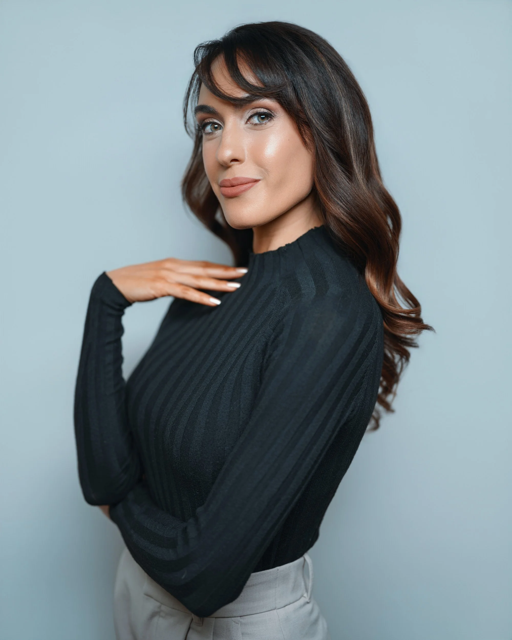 Team headshot of woman in black top against light blue studio background
