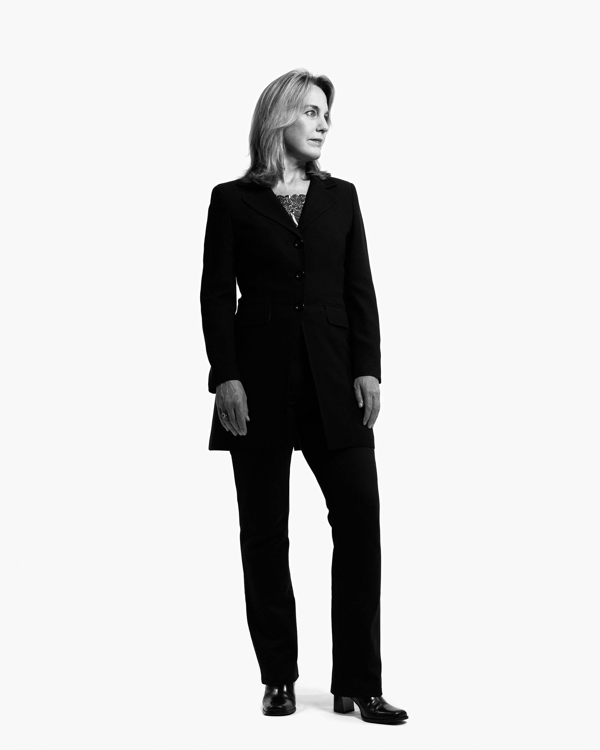 Full-length professional headshot of woman in black blazer and pants against white background