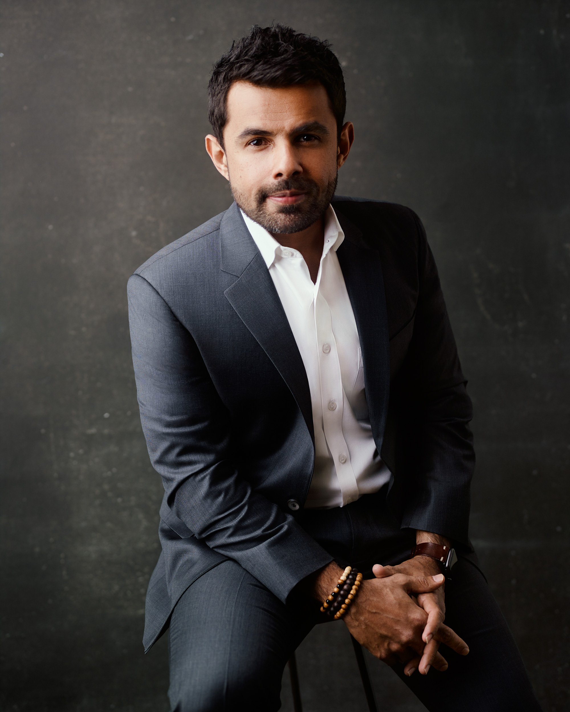 Corporate team headshot of man in gray suit and white shirt with neutral backdrop