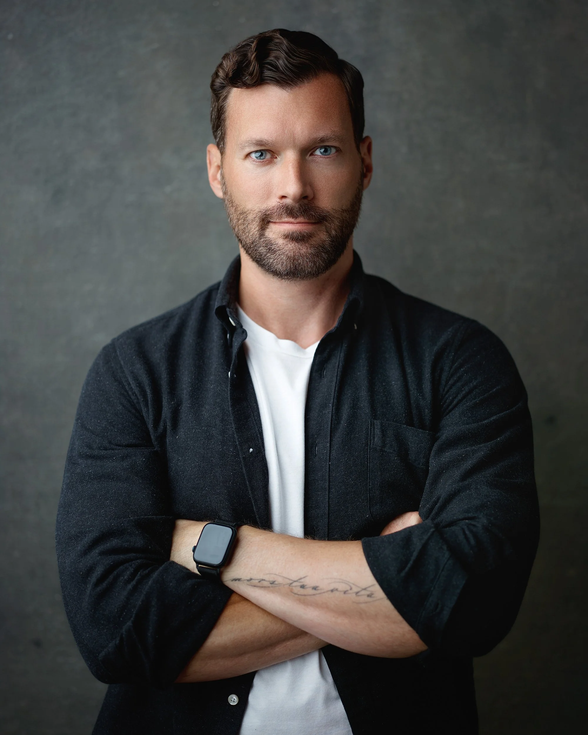 Company headshot of man in dark shirt against gray textured studio backdrop
