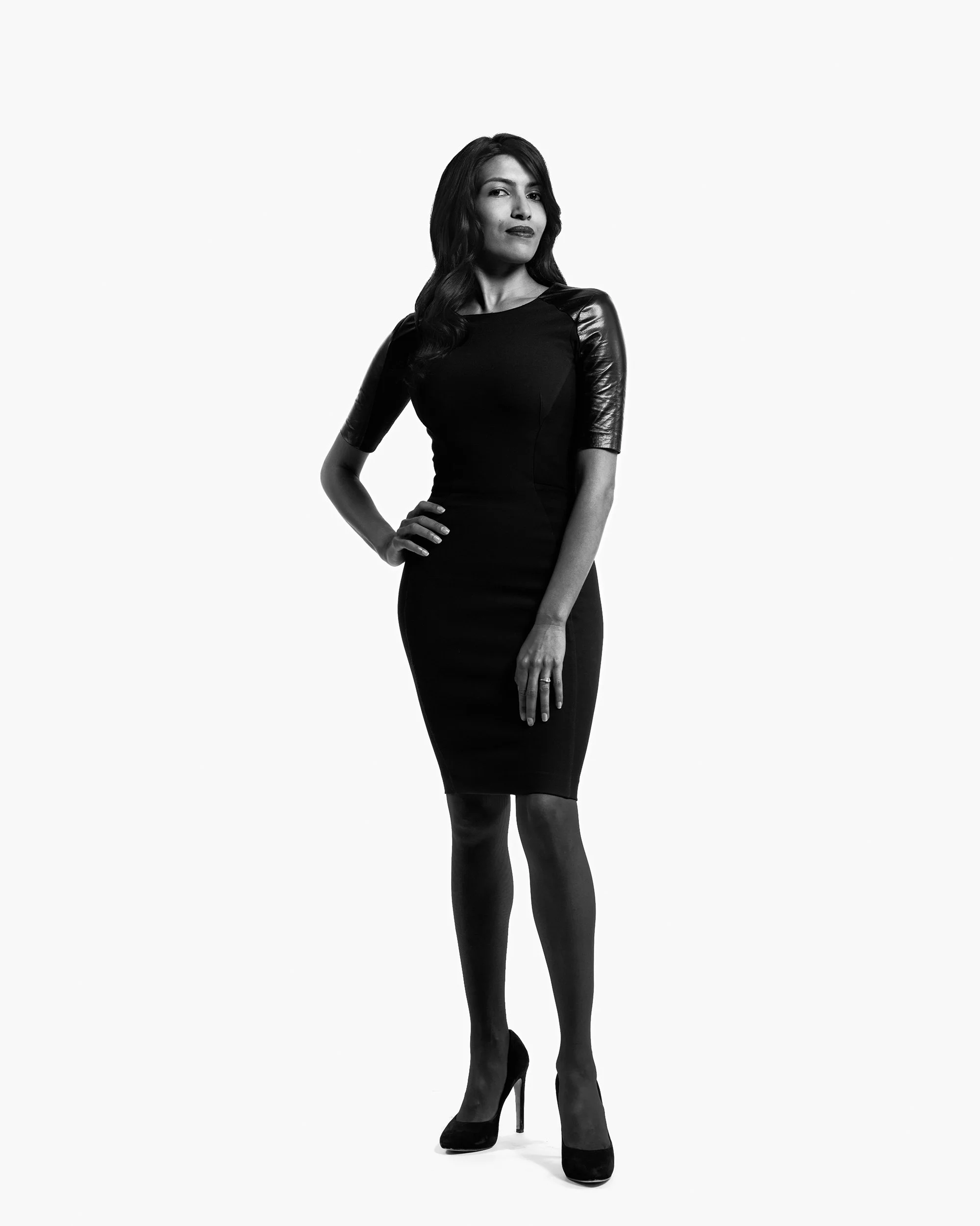 Full-length company headshot of woman in black dress against white studio background
