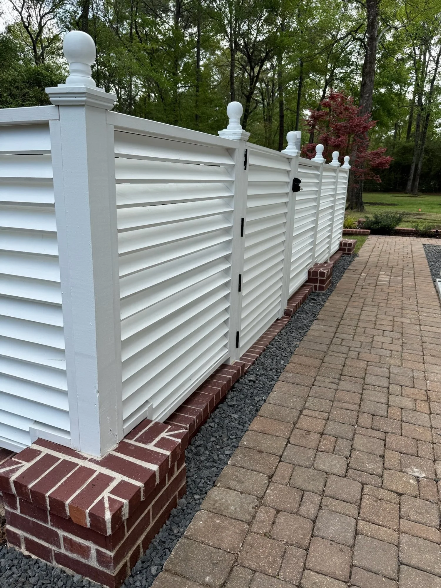 White louvered screen on red brick podiums hiding the generator beside new lawn and beds at Red Oak Ranch, Lake Forest Drive, Conroe TX
