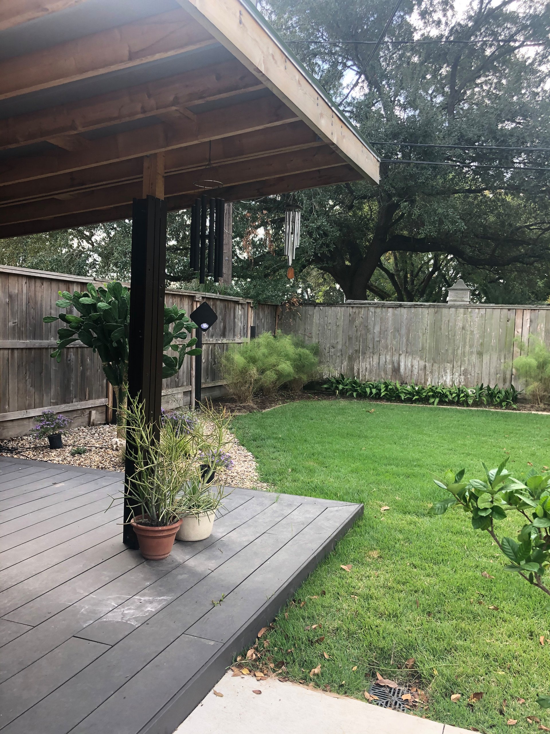 The back yard patio of bbq hut with our favorite recycled bamboo decking ceramic tiles. A cool cantilevered cedar,  tin roof and zoysia lawn to play in.  