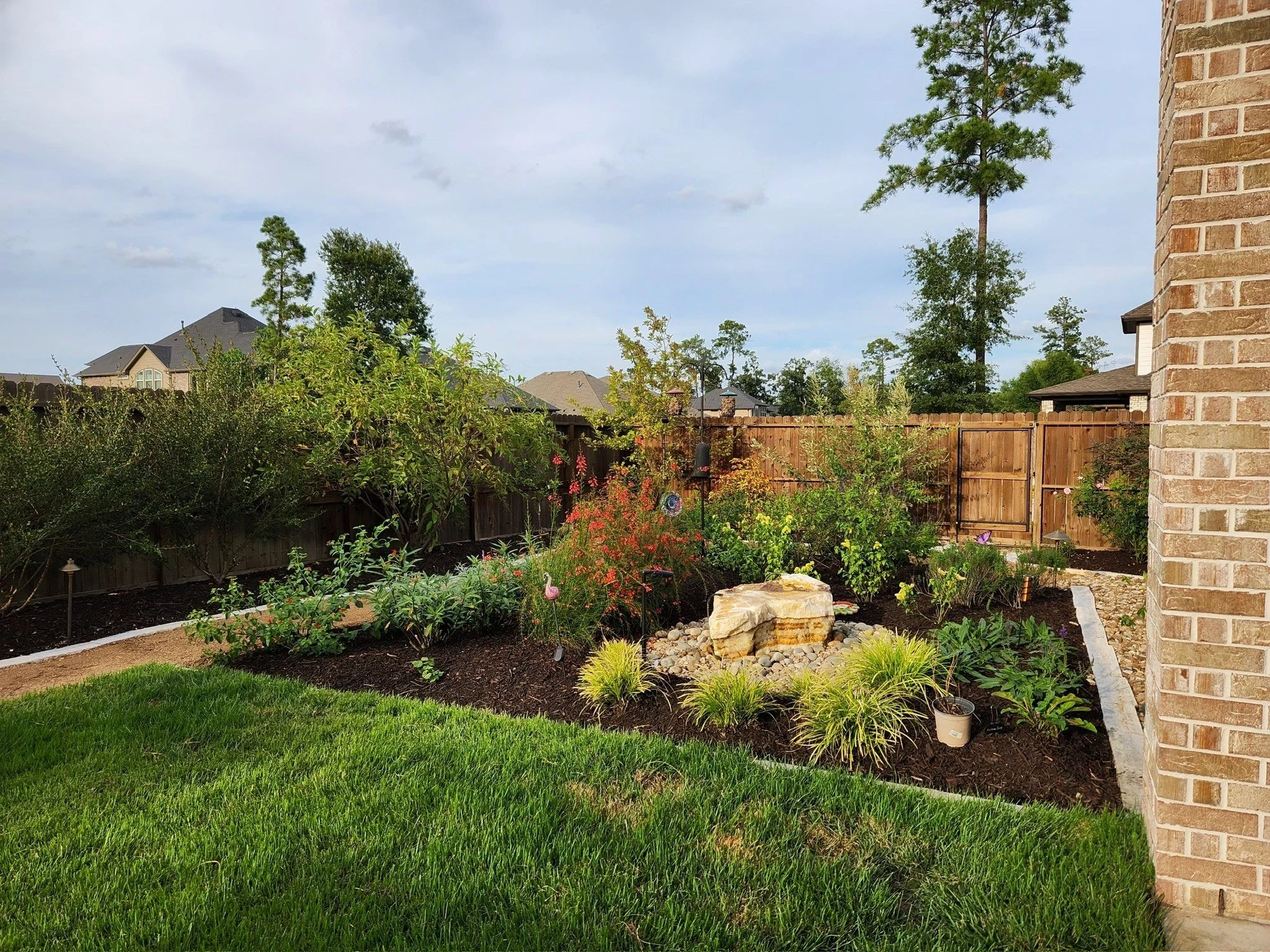 native pollinator garden with boulder water feature and limestone-edged beds