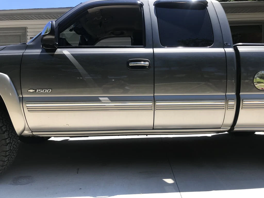 Side view of a gray Chevrolet Silverado 1500 pickup truck parked on a driveway.