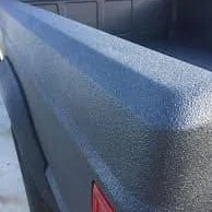 Close-up of a textured, dark-colored truck bed cover on a pickup truck.