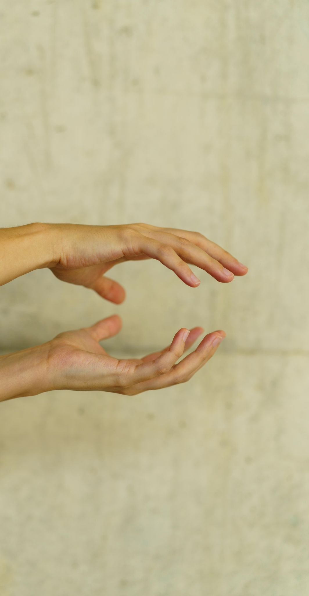 Two hands with fingers gently curved, positioned against a beige textured background.