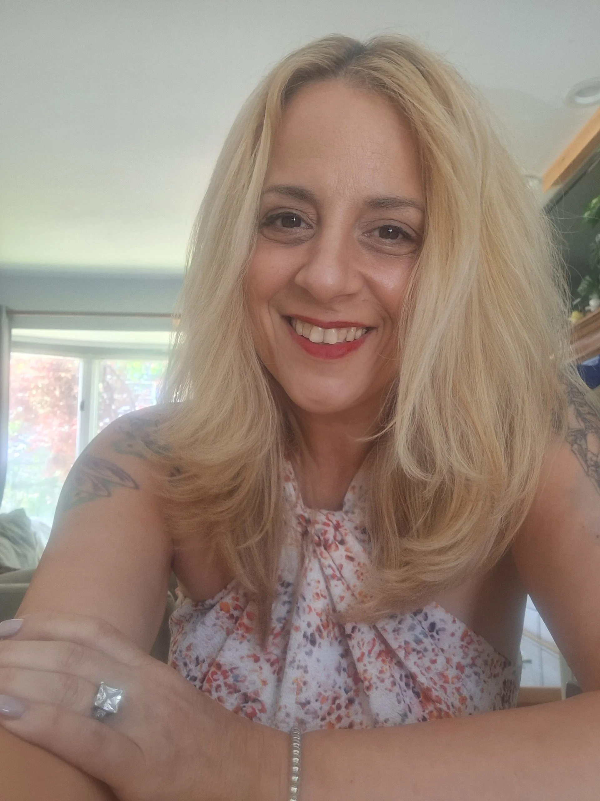 Portrait of a woman with blonde hair wearing a white top.