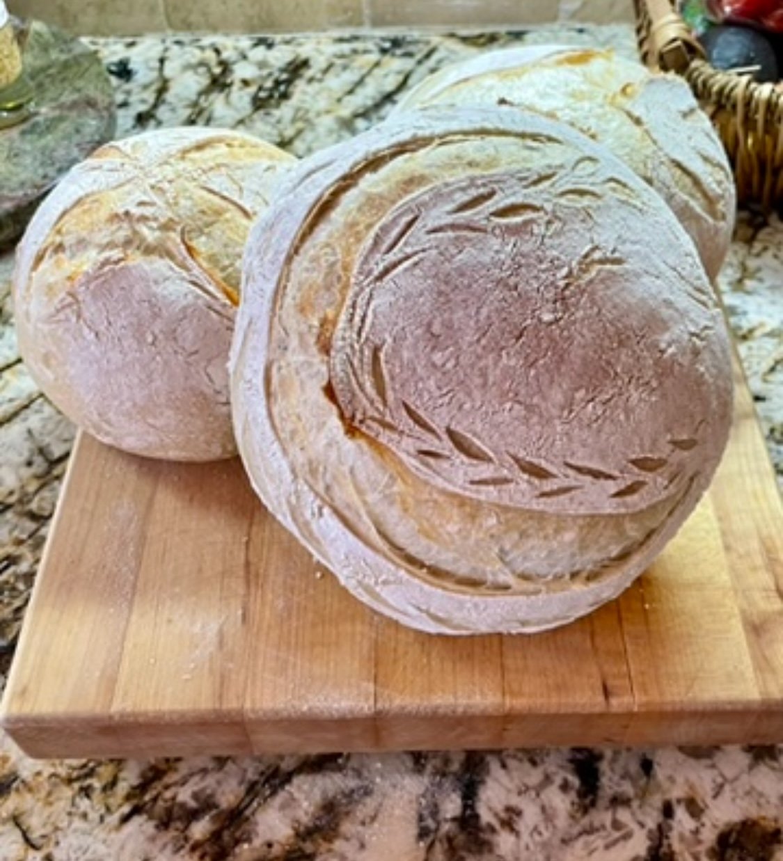 Three large rounds of bread on a wooden cutting board.
