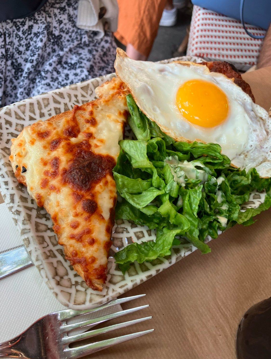 Plate with a slice of cheese pizza, a fried egg, and a green lettuce salad.