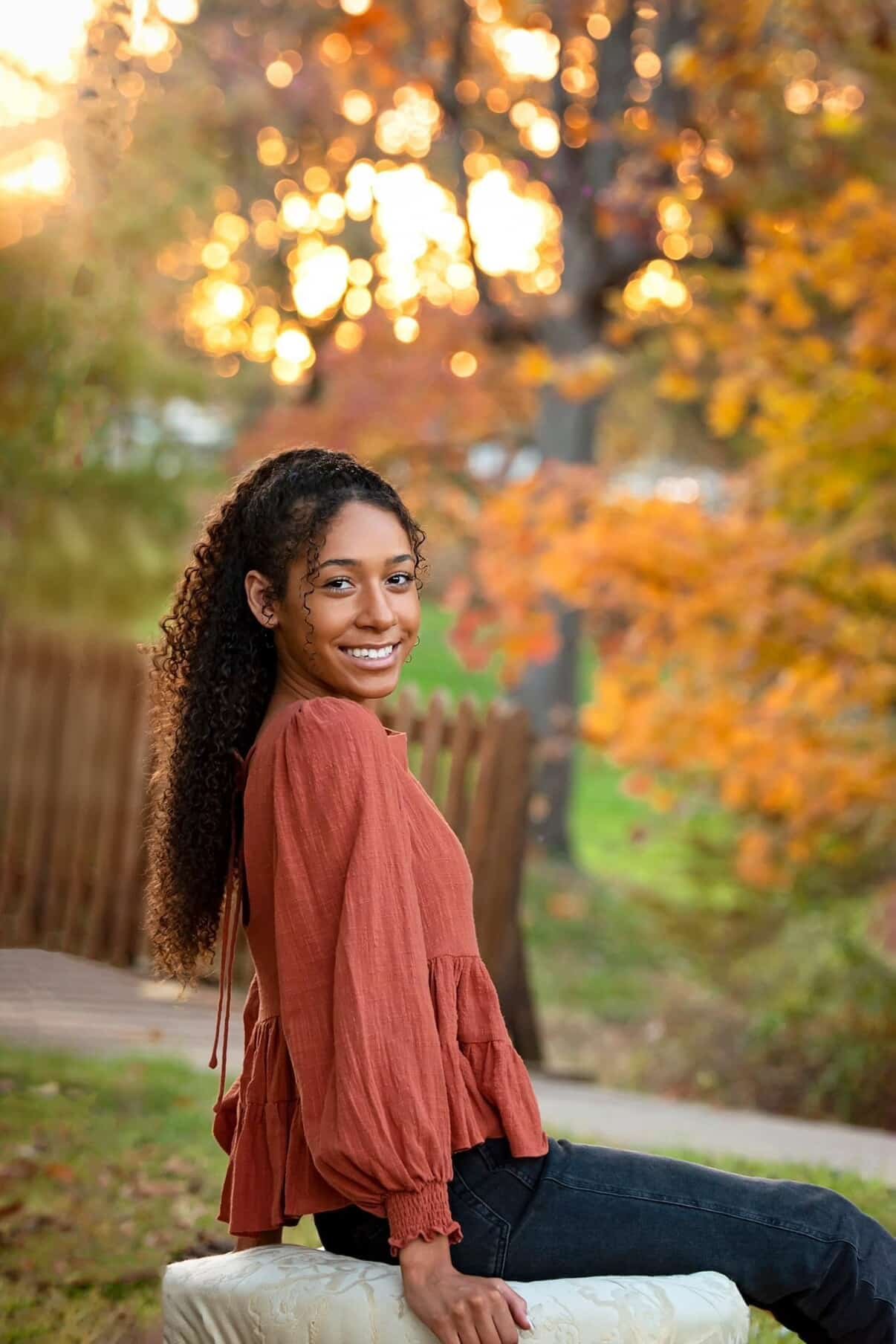 young, smiling woman surrounded by fall foliage