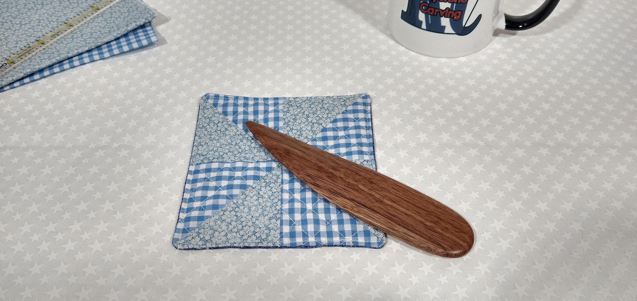 Display of a handmade walnut point turner laying on a blue and white checkered pillow