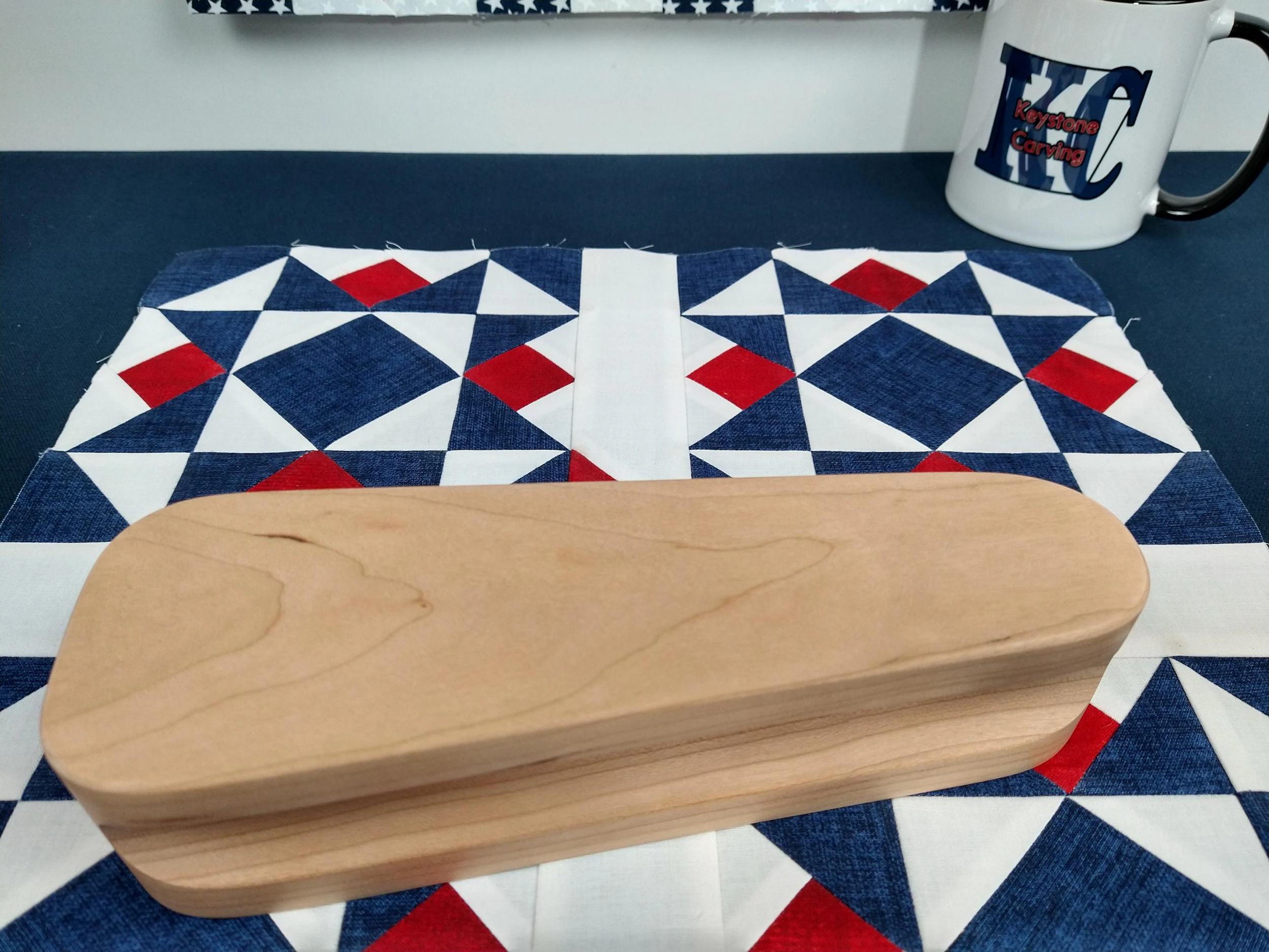 eight and a half inch tapered cherry hardwood tailors clapper setting on an Americana quilt block