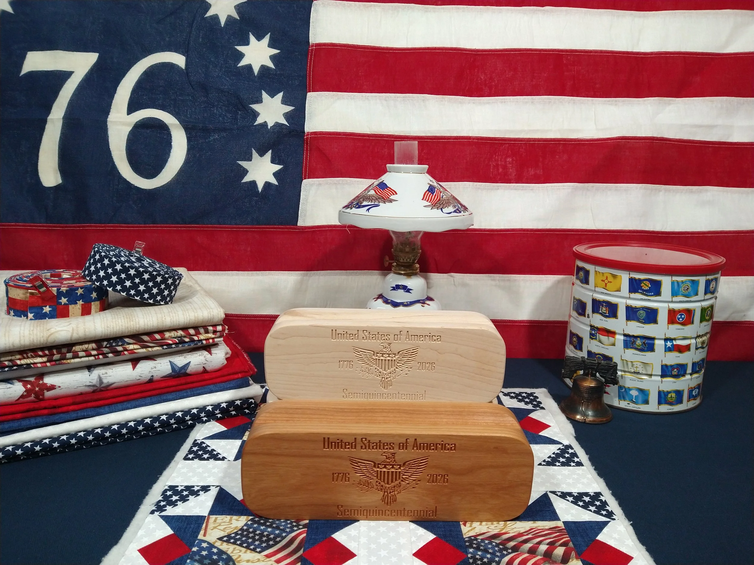 USA 20th birthday quilters clappers in hard maple and cherry. 1776 American flag in back. Red, white, and blue quilt block.