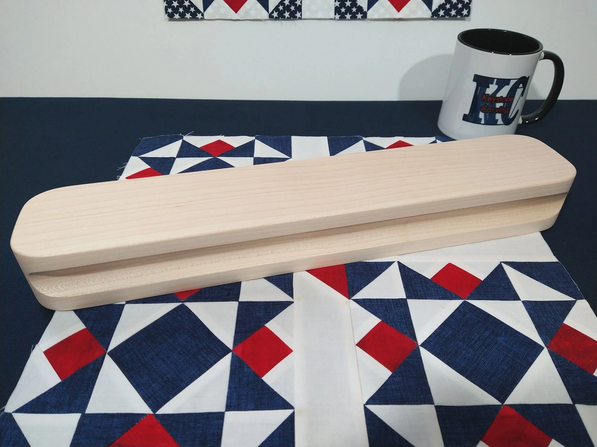 heavy hard maple tailors clapper laying on a red, white, and blue quilt block