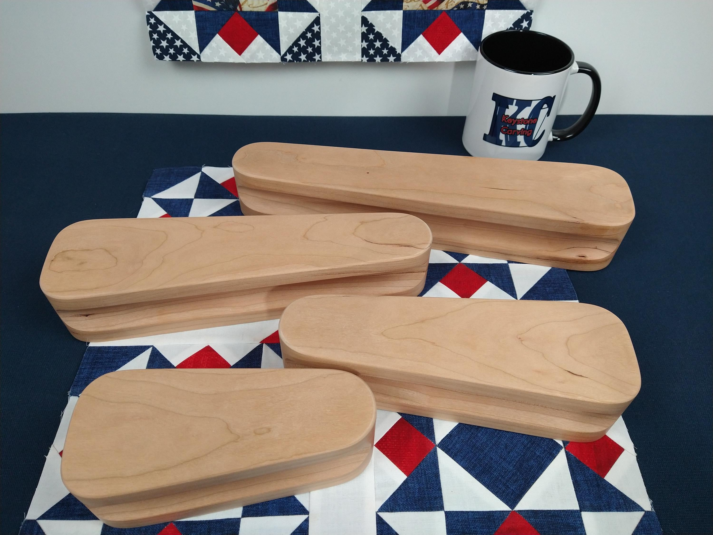 display of four different sized cherry tapered tailors clappers arranged flat on a patriotic quilt block