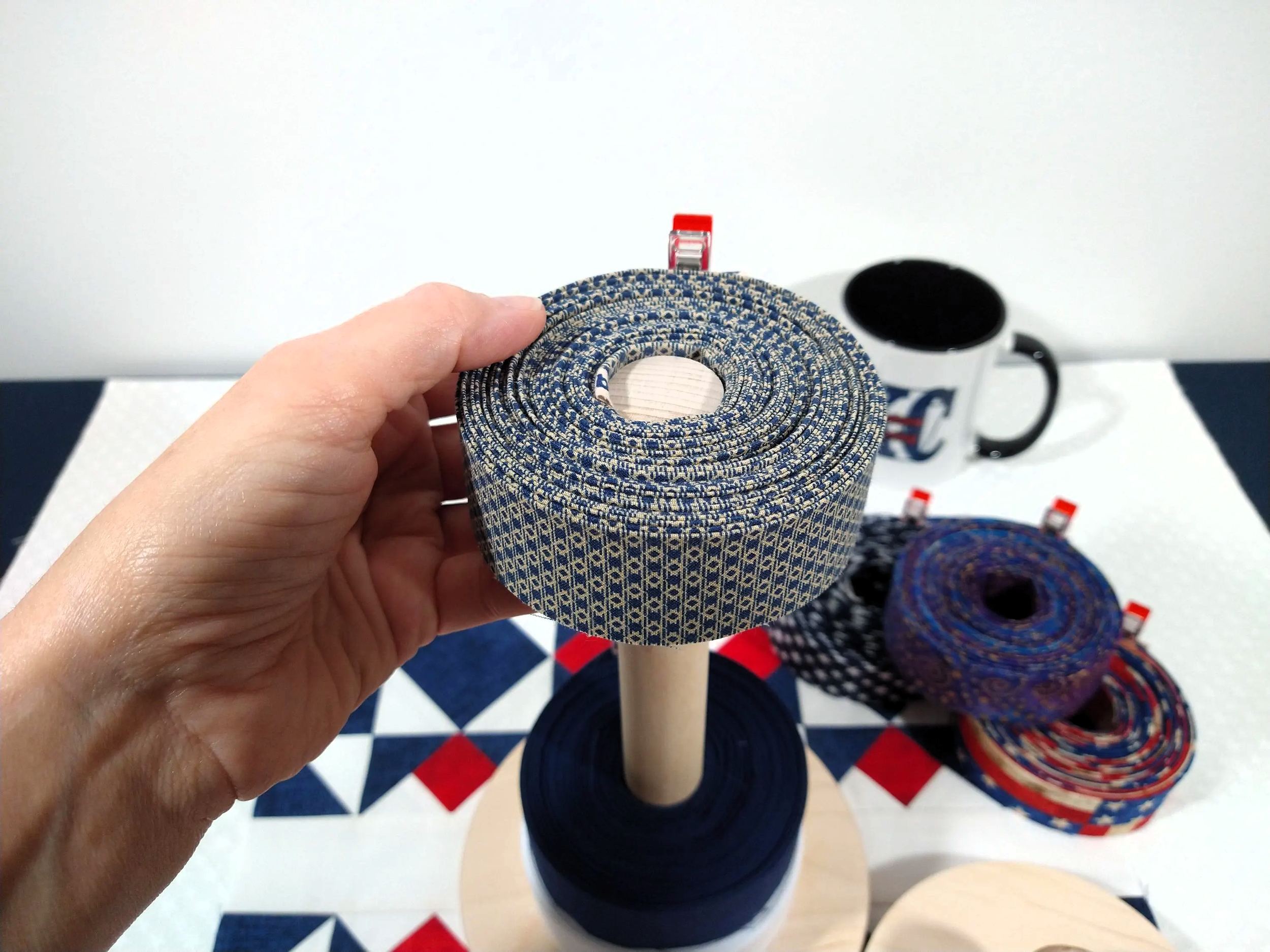 showing a roll of quilt binding being slid down onto the quilt binding storage organizer's one inch spindle