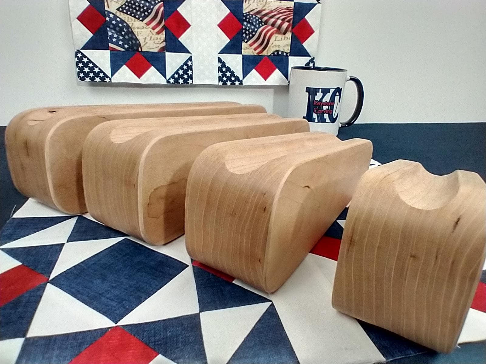 display of four different sized cherry tapered tailors clappers arranged on edge looking at the back edge on a patriotic quilt block