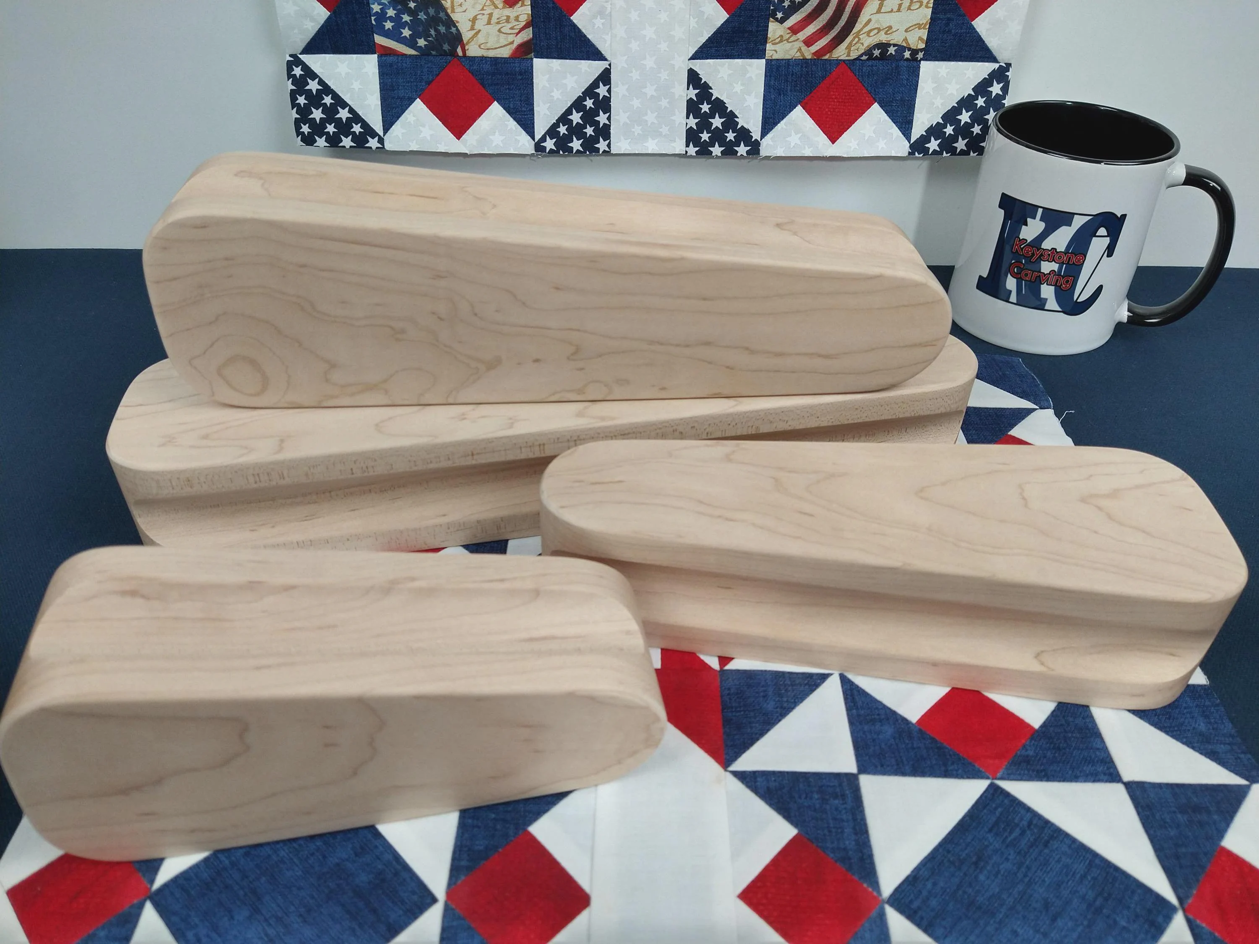 display of four different sized maple tapered tailors clappers arranged on a quilt block