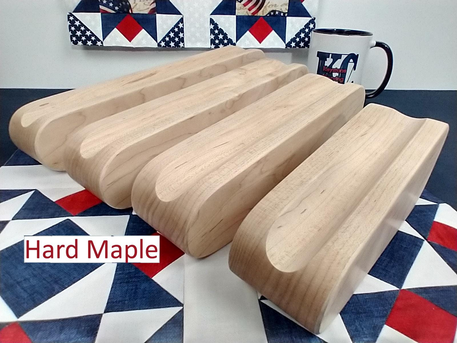 display of four different sized hard maple tapered tailors clappers arranged on edge looking at the front edge on a patriotic quilt block