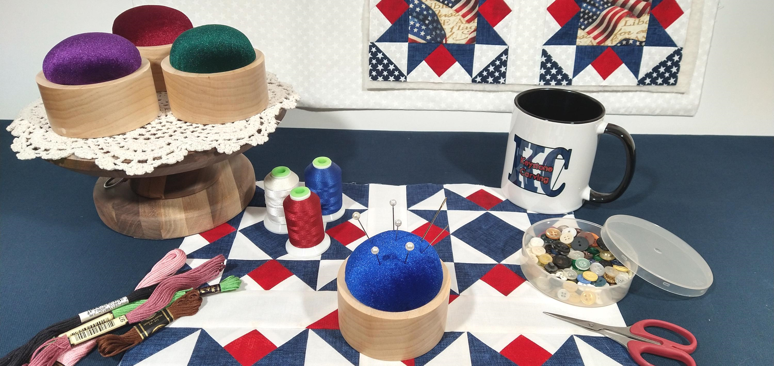 Beautiful display of Keystone Carving Pincushions featuring royal blue, dark green, Burgundy, and purple.