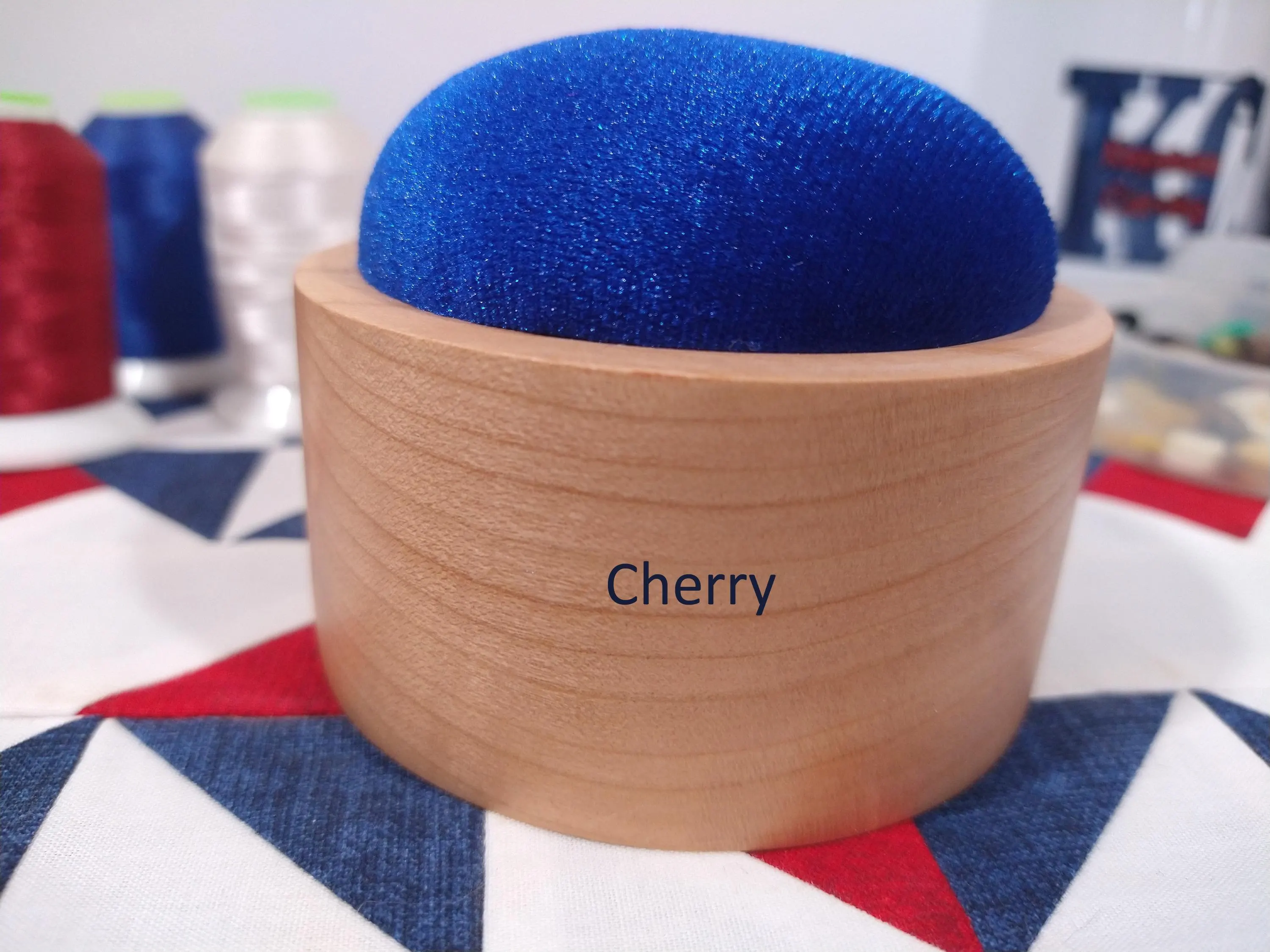 Zoomed in front side of a cherry wood pincushion with royal blue velvet fabric