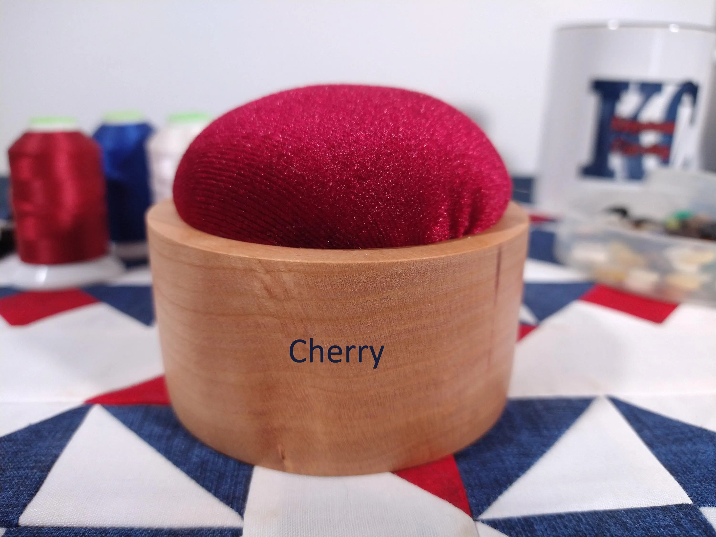 Zoomed in front side of a cherry wood pincushion with Burgundy velvet fabric