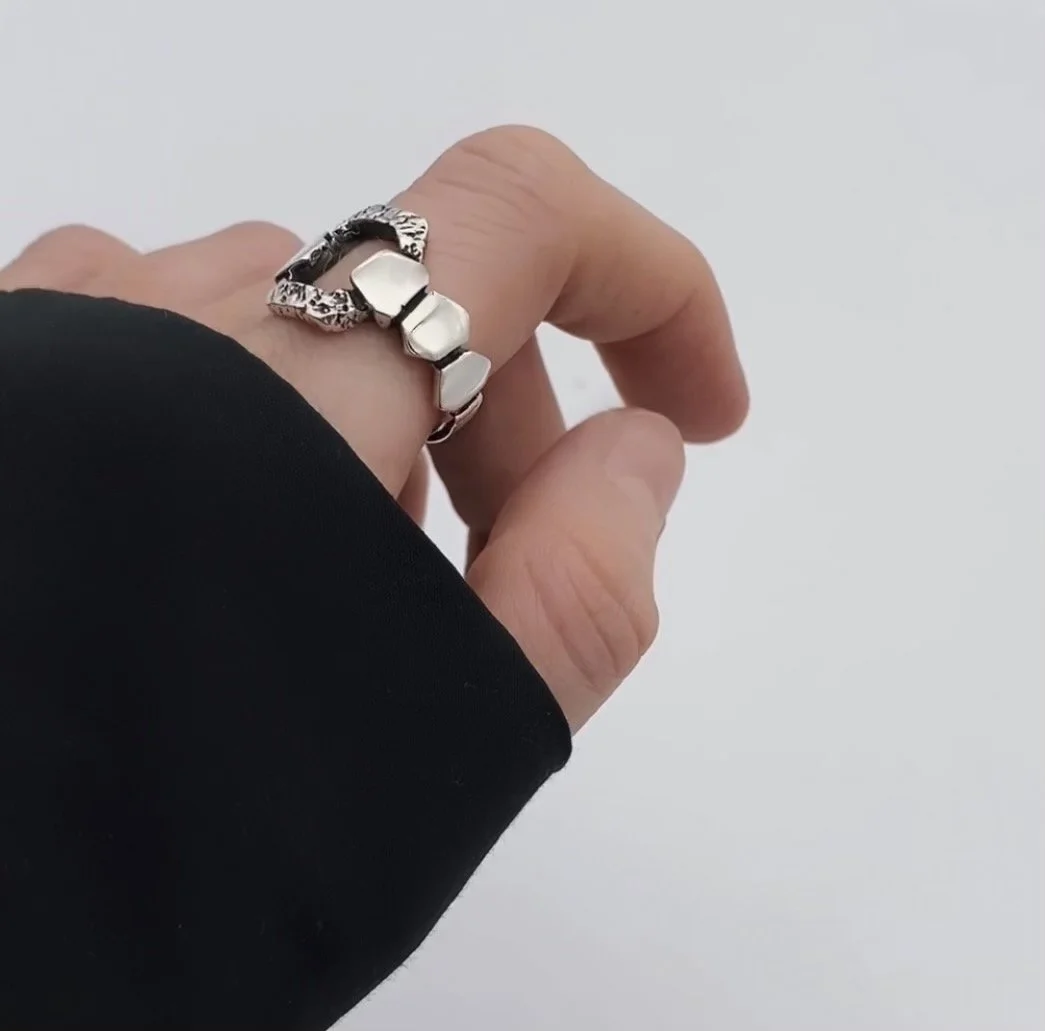High quality silver ring, created with structural complexity, whimsical shape and unique patterns. The square shaped textured part with a hole in the middle is being wrapped by the ring itself.