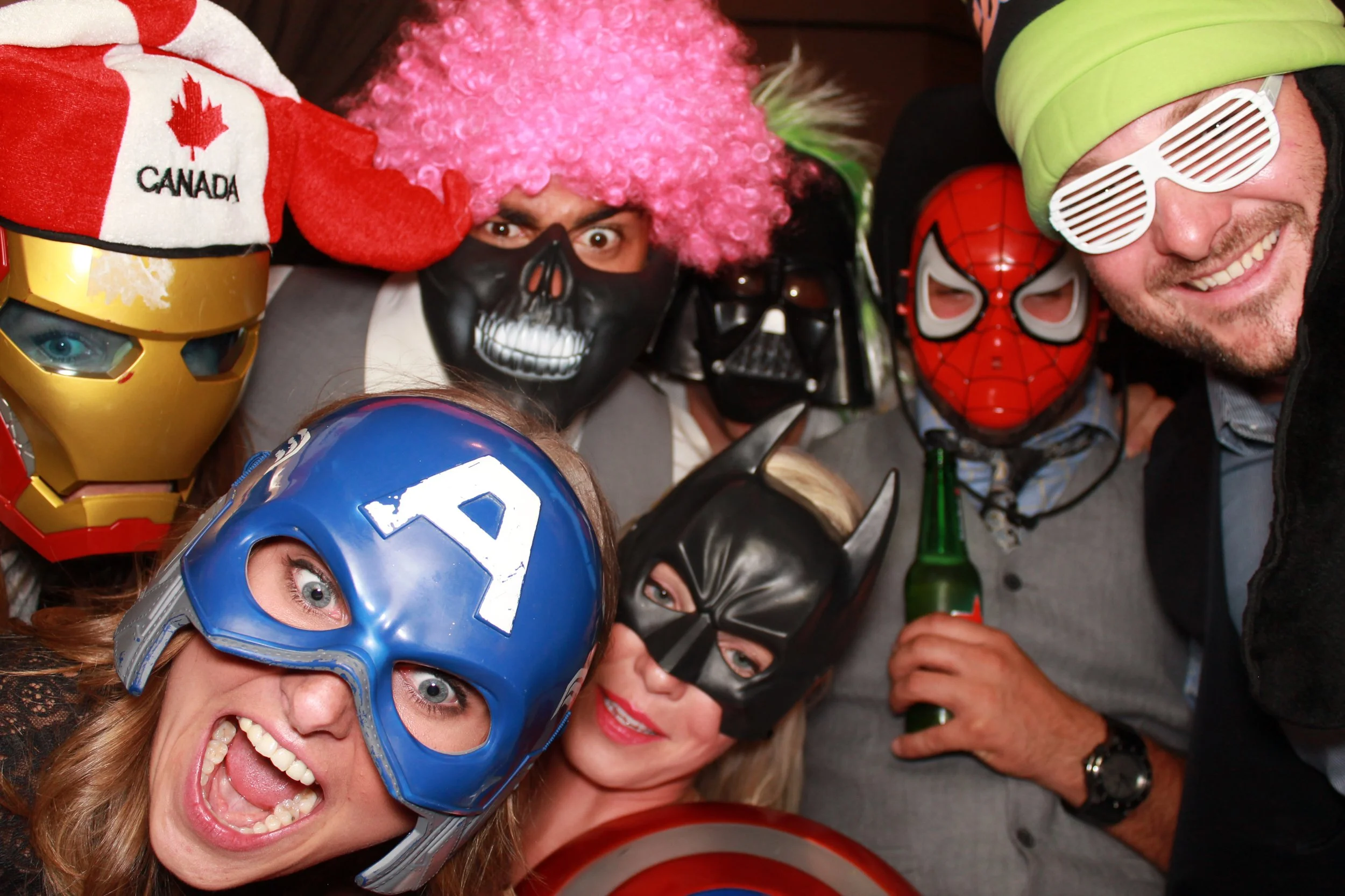  A group of people in various superhero and villain costumes are posing and smiling for the camera at a lively party, utilizing an event photo booth with props in Burnaby. 