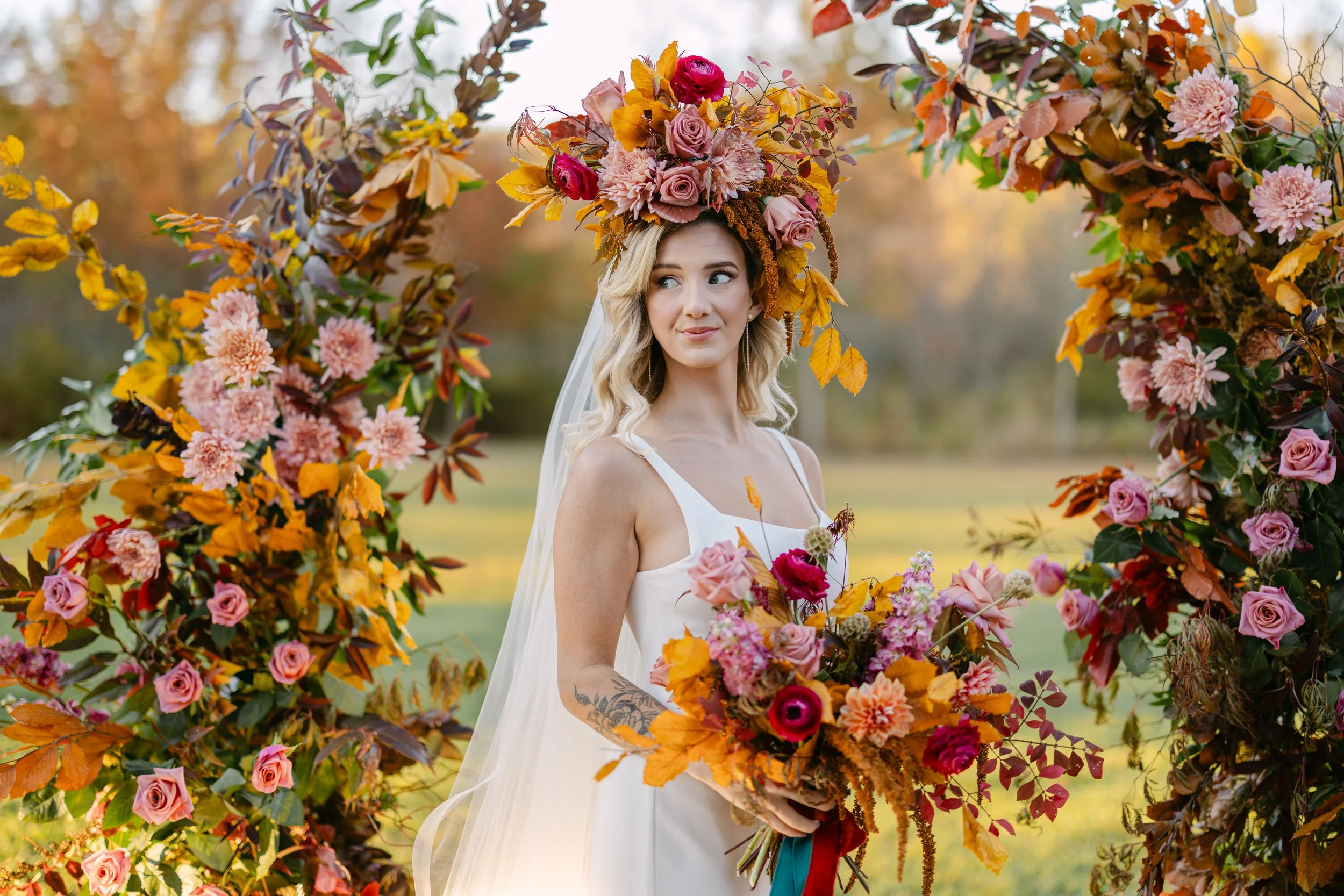 Colorful, full wedding floral installation with ceremony arch and coordinating bouquet at the Village Green in the mountains of Cashiers, NC