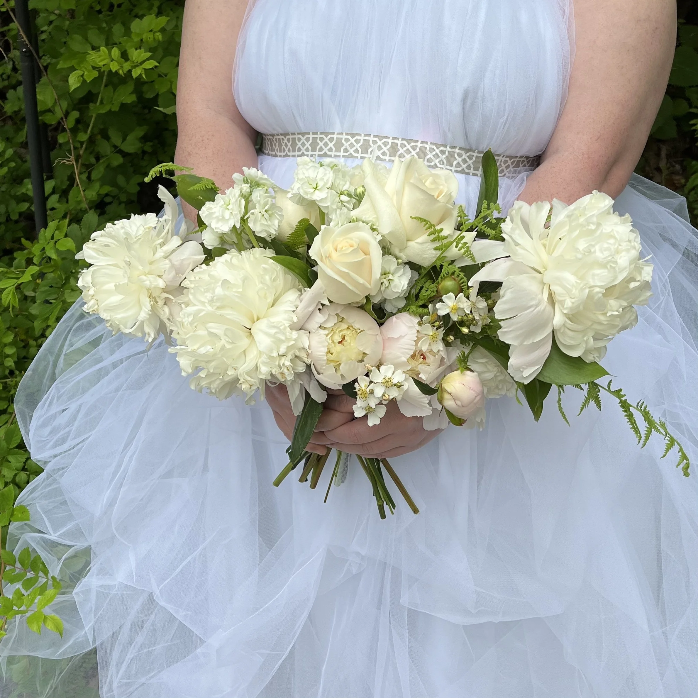 Bride holding a whimsical garden style bouquet during a lakeside mountain ceremony.