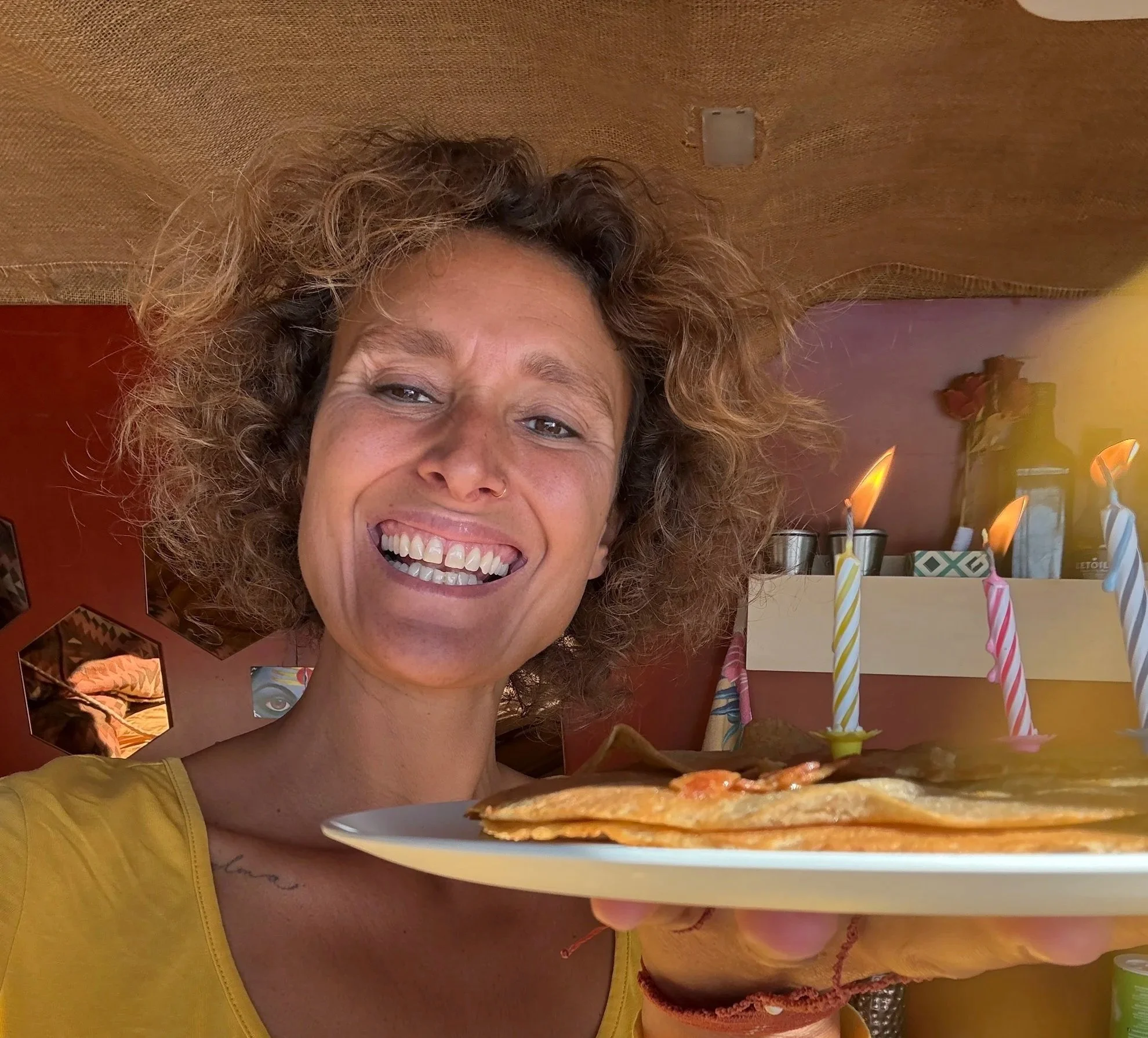 Close-up van Eveline met een bord pannenkoeken en drie kaarsjes tijdens een persoonlijk moment van vertraging, zachtheid en verbinding met haar innerlijk kind.