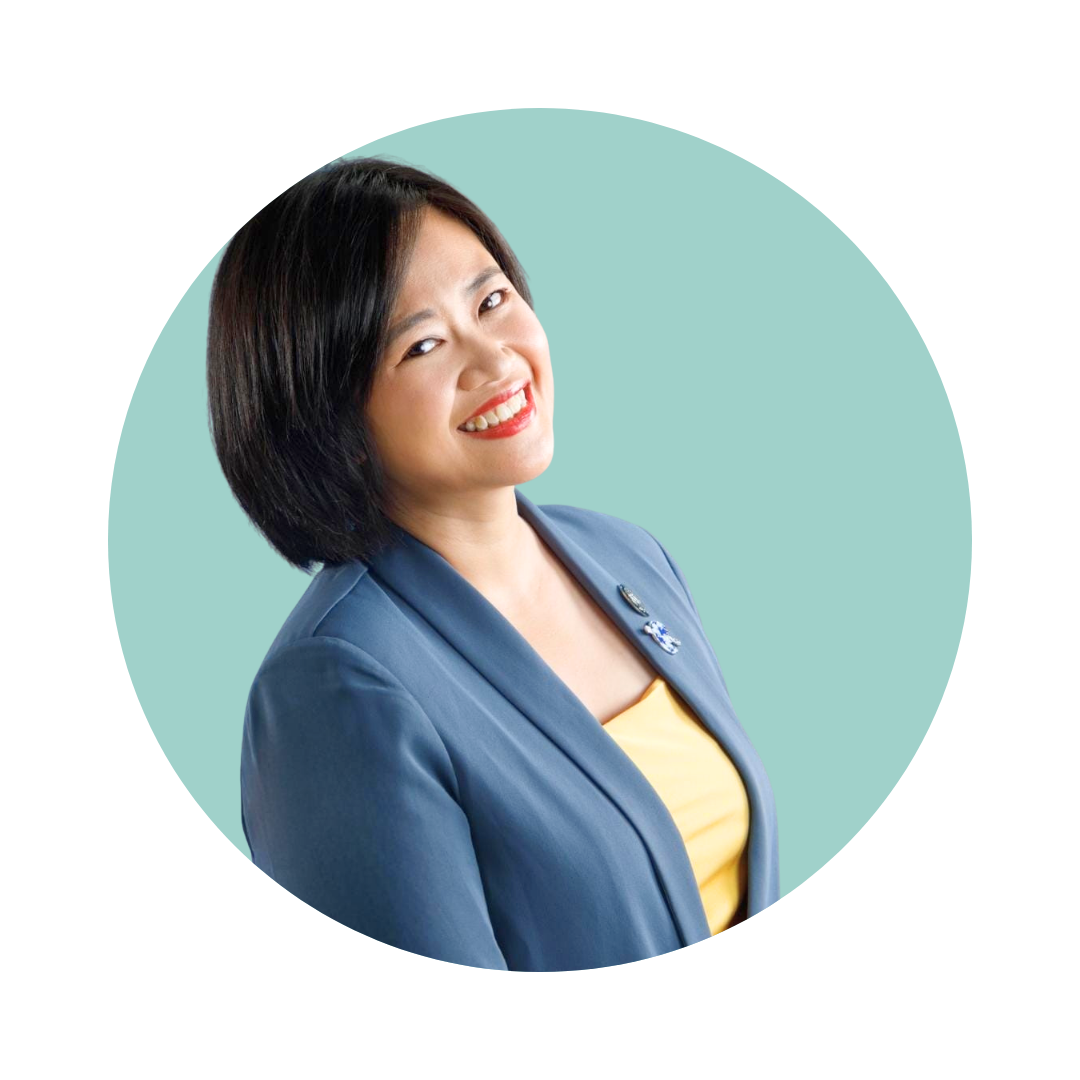 Black and white portrait of a smiling woman with shoulder-length hair, wearing a blazer and a necklace, against a plain background.