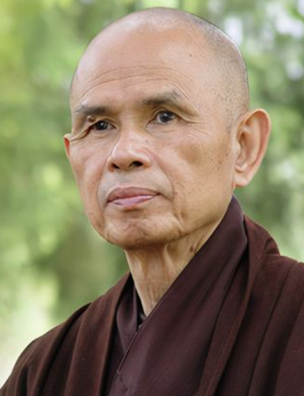 A historic temple with intricate architectural details during a colorful sunset with trees in the foreground.