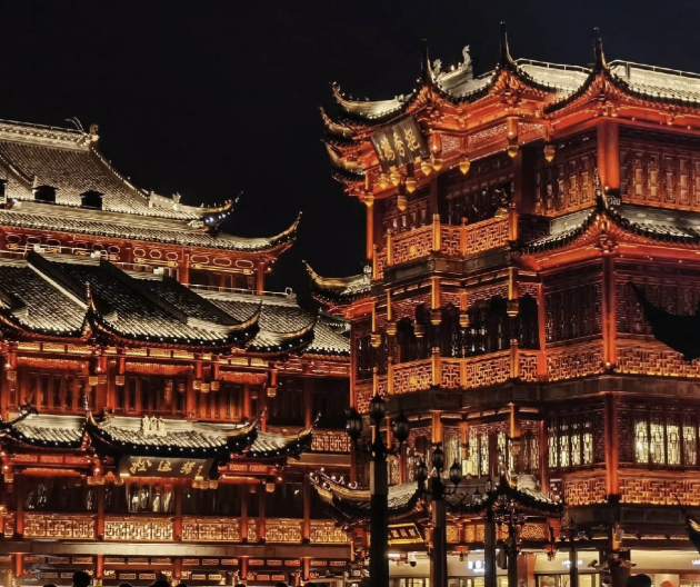 View of a riverside with boats, old buildings, and temples in the background during sunset.