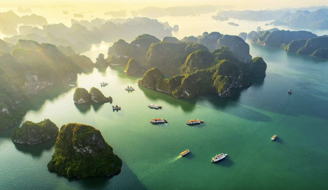 Stone sculpture of a meditative figure seated cross-legged with hands in a prayer gesture, surrounded by intricate carved patterns and mythical creatures.
