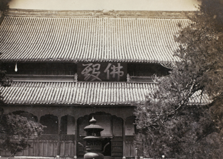 A historic temple with intricate architectural details during a colorful sunset with trees in the foreground.