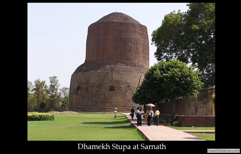 A large, ancient brick stupa called Dhamek Stupa at Sarnath, with a pathway and some visitors walking nearby.