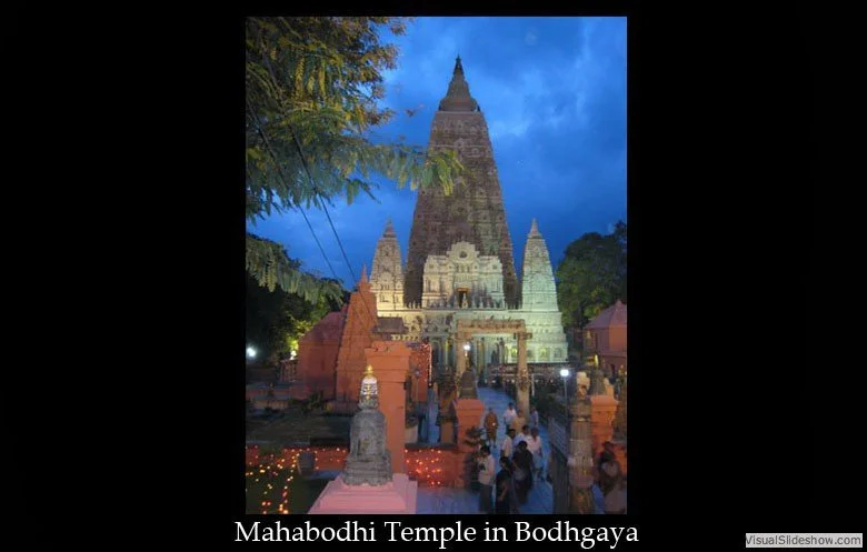 Mahabodhi Temple in Bodh Gaya at dusk, with a tall central spire, surrounding smaller structures, and people gathered around in the foreground.