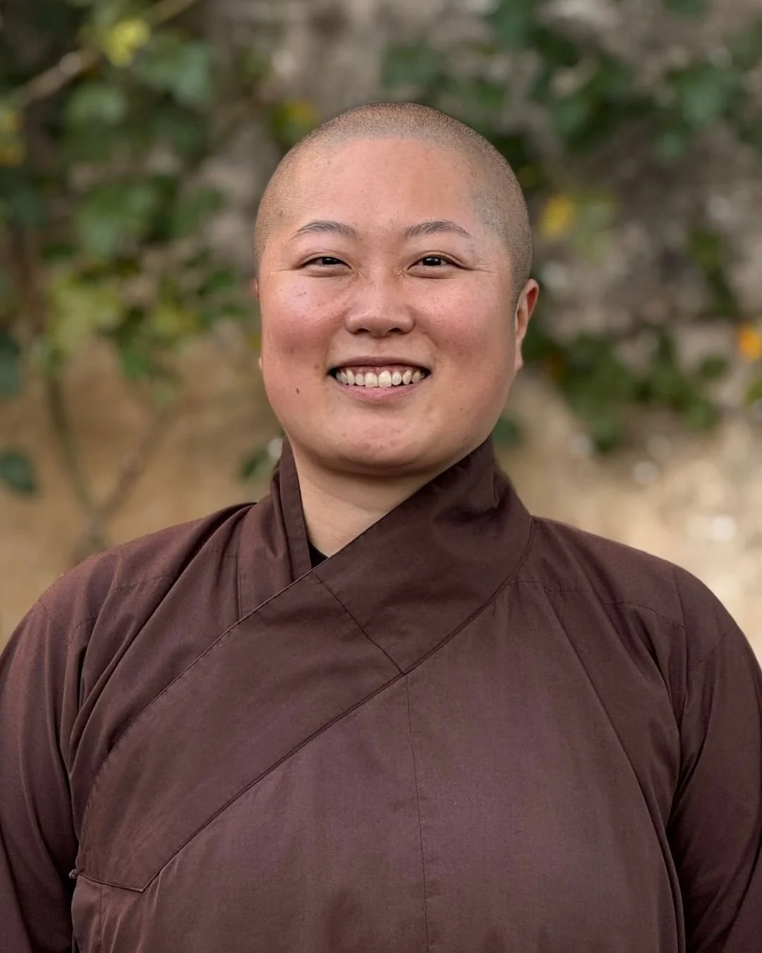 A group of people attending a seminar, with the focus on a smiling, bald man wearing a dark brown jacket.
