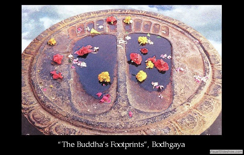 A circular stone water fountain with two sections, decorated with colorful flowers floating on the water, located at Bodhgaya, titled 'The Buddha's Footprints'.