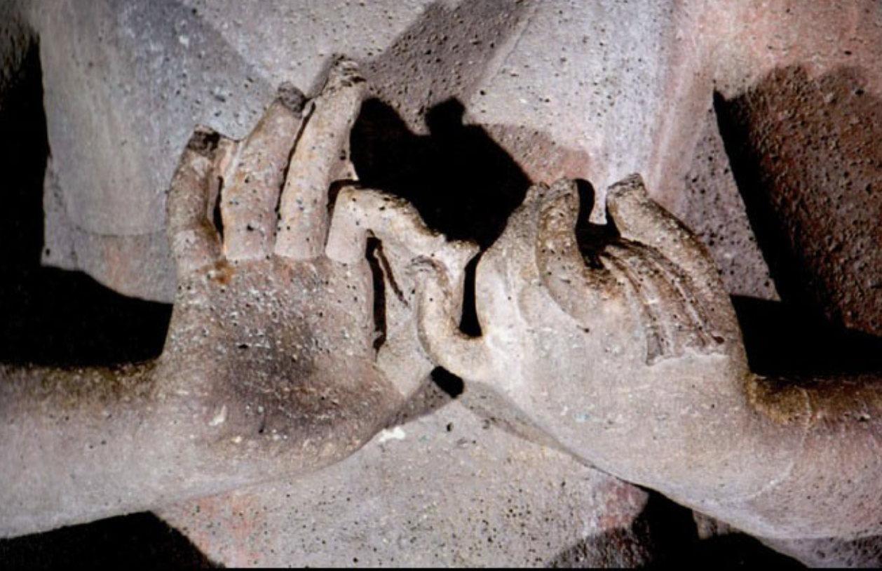 Close-up of two stone sculptures of hands touching, likely part of an ancient artifact or monument.